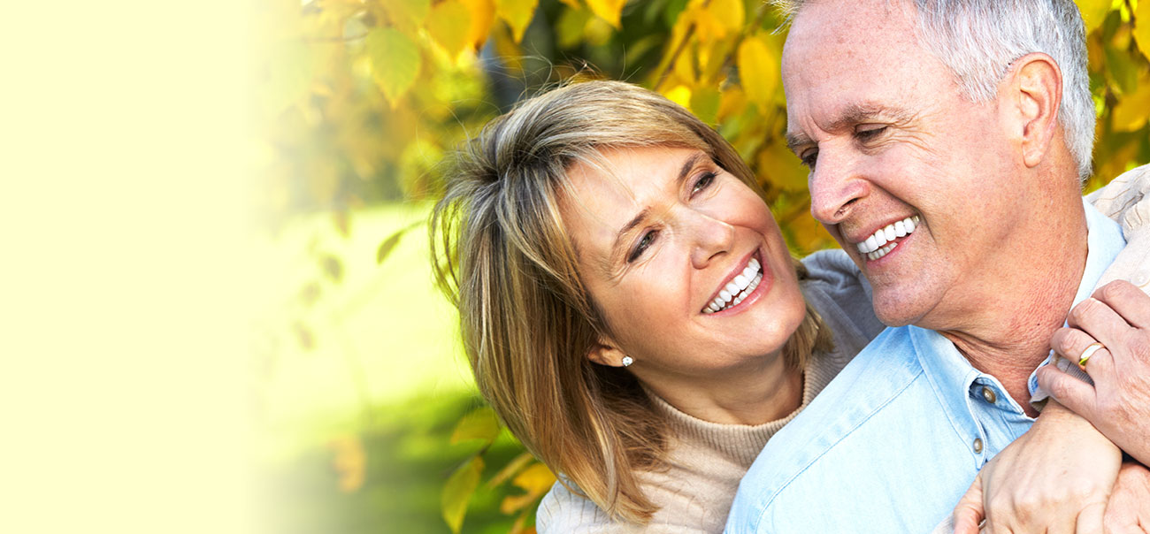 Older man and woman smiling at each other after visiting their dentist in Tysons Corner